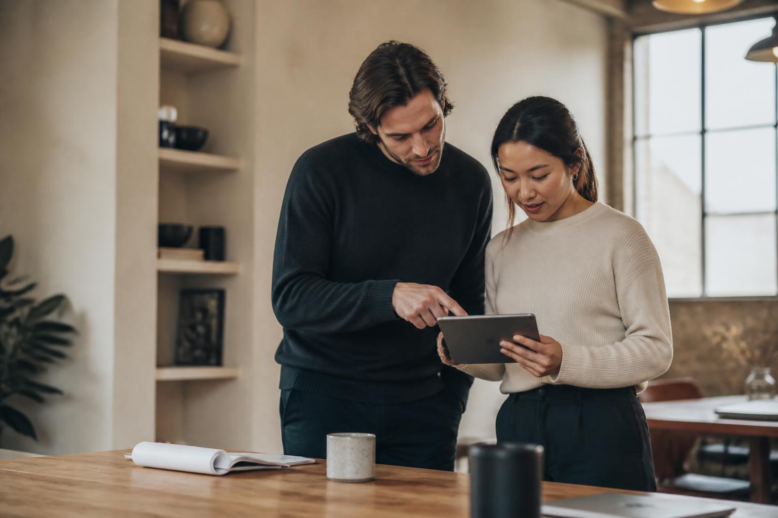 Two colleagues reviewing customer feedback together on a tablet